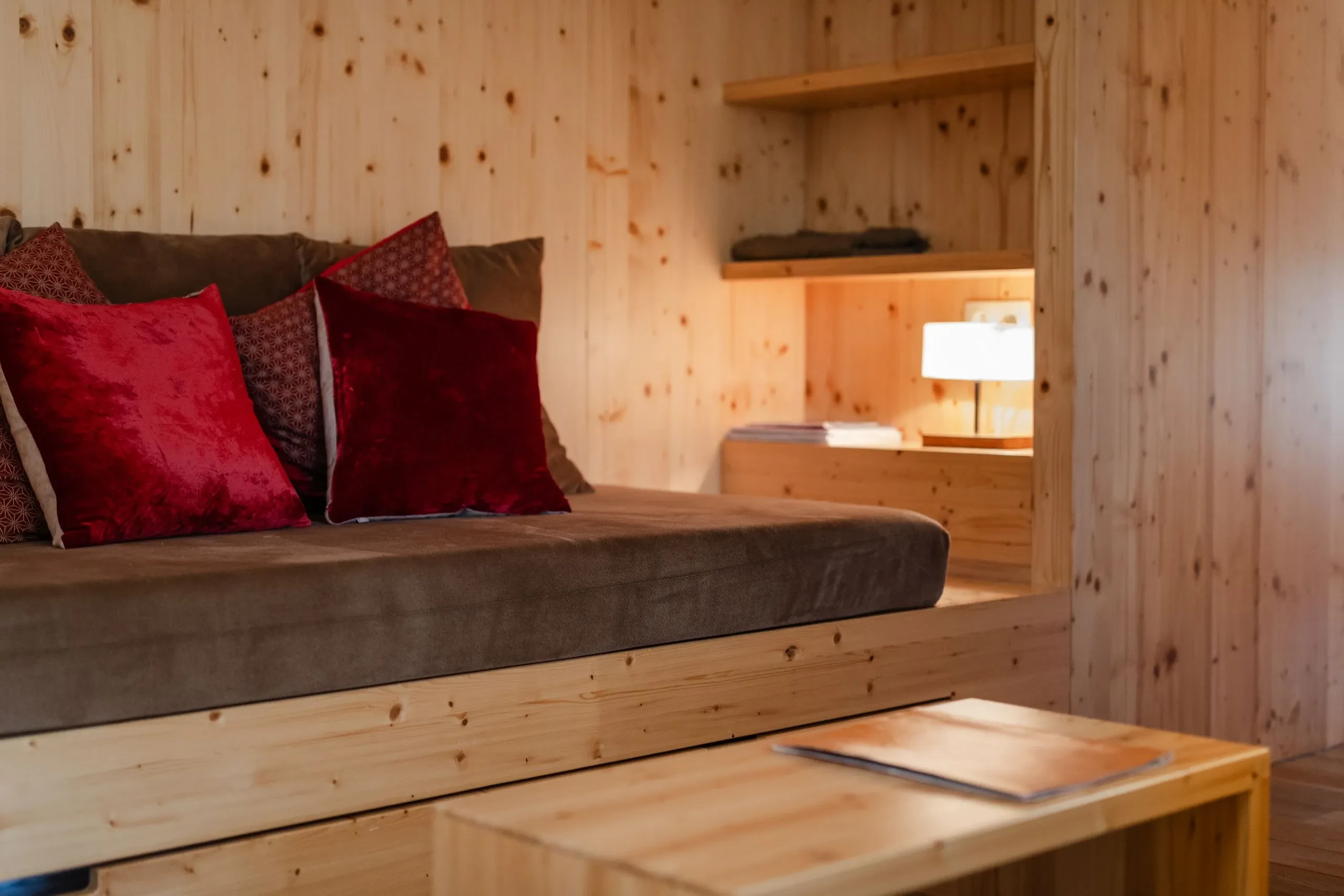Cozy wooden room with red pillows.